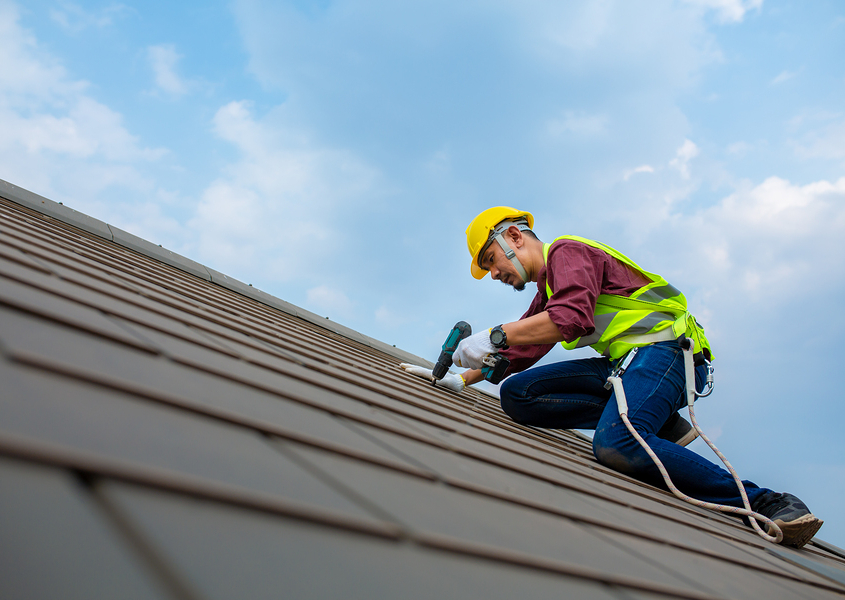 Worker Bee roofer in a yellow hard hat repairing shingles